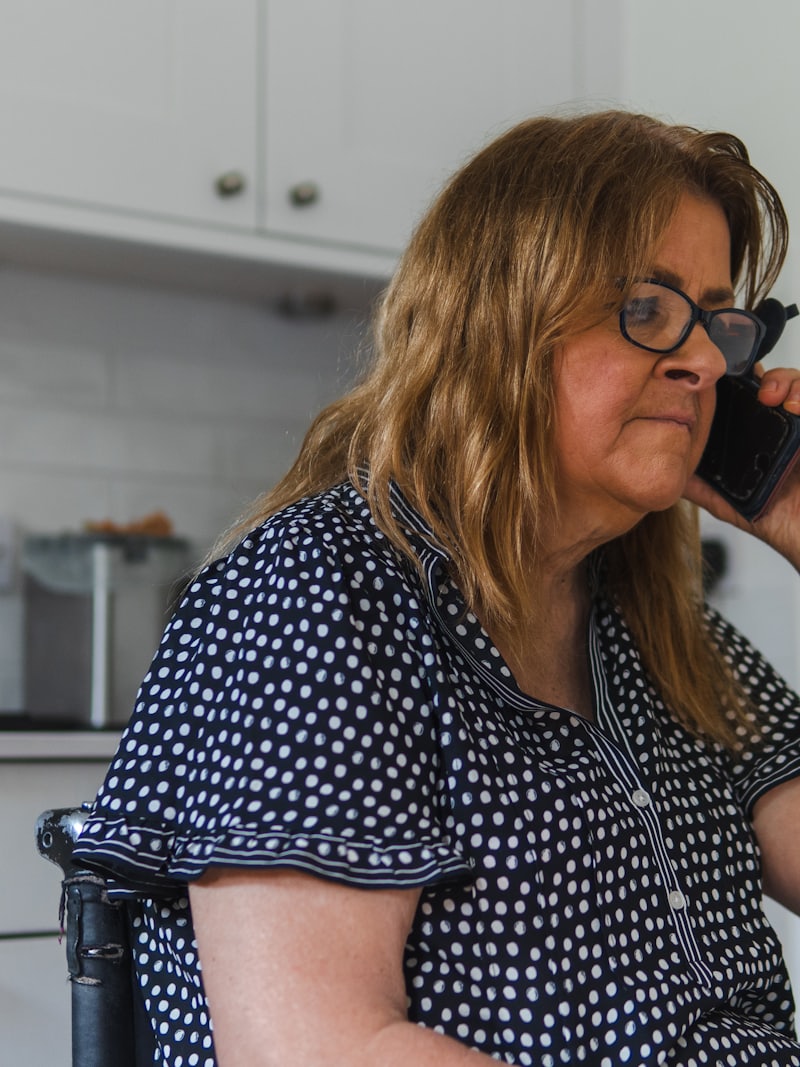Mulher ao telefone na cozinha de casa.
